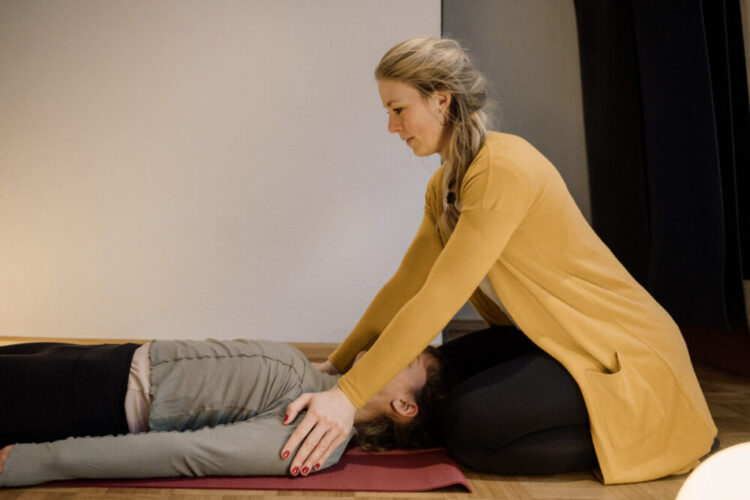 Es wird eine Frau gezeigt, die einer anderen Frau bei der Atemarbeit unterstützt und anleitet.